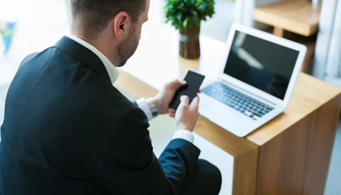 Homem sentado mexendo no celular representando vendas pelo celular.