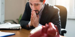 homem esperando ligação em sua corretora de seguros, com cara de desesperando, aprendendo como abordar um cliente para vender seguro.