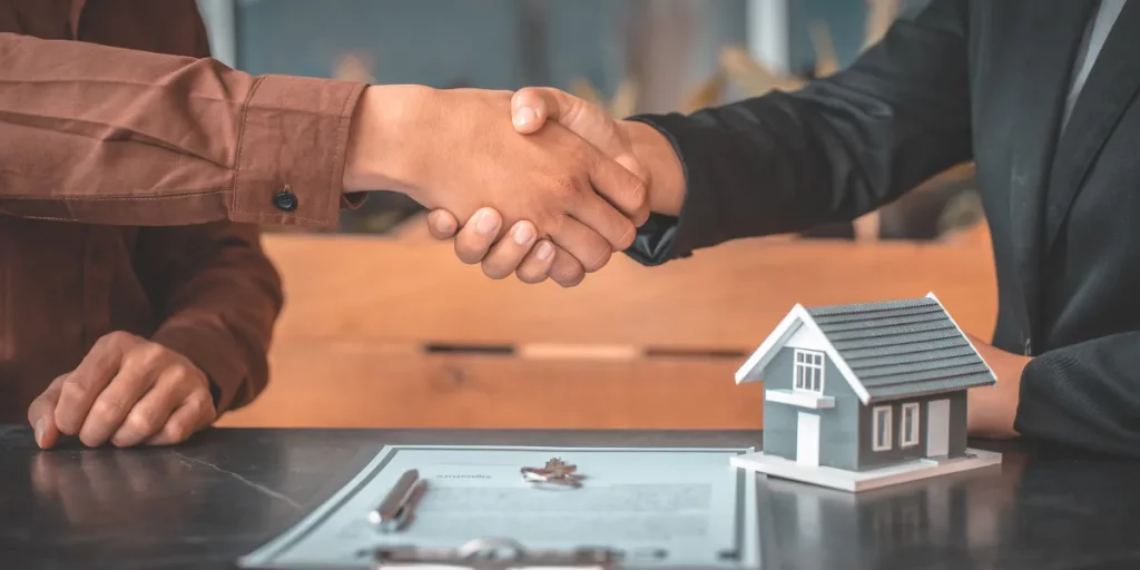 Cliente e corretor de seguros apertando as mãos, após fechar seguro residencial. como vender mais seguros.