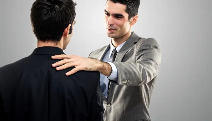 homem tocando o ombro do outro, representando estratégias de persuasão na abordagem de cliente de seguro.