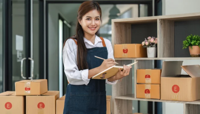 Logística reversa no e-commerce representado por uma mulher embalando pedidos.